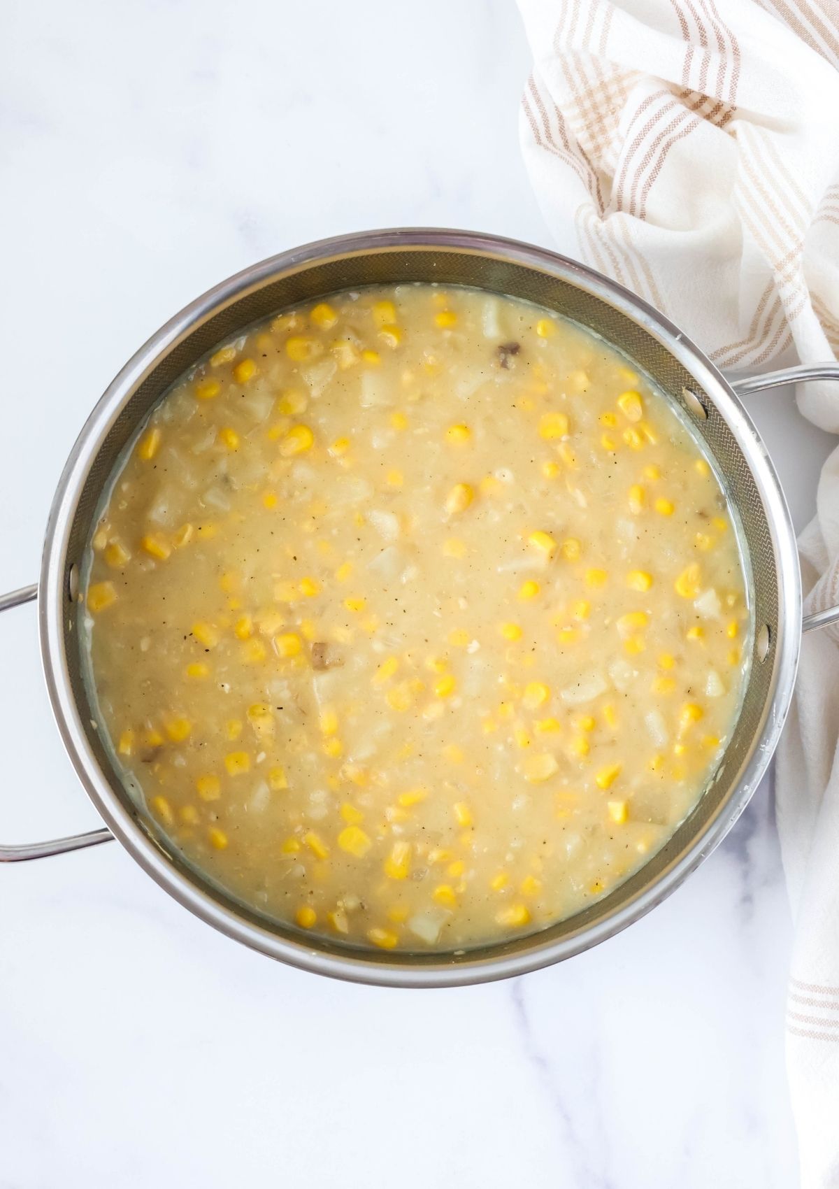 Overhead view of a stock pot filled with potato corn chowder made with canned corn and frozen potatoes.
