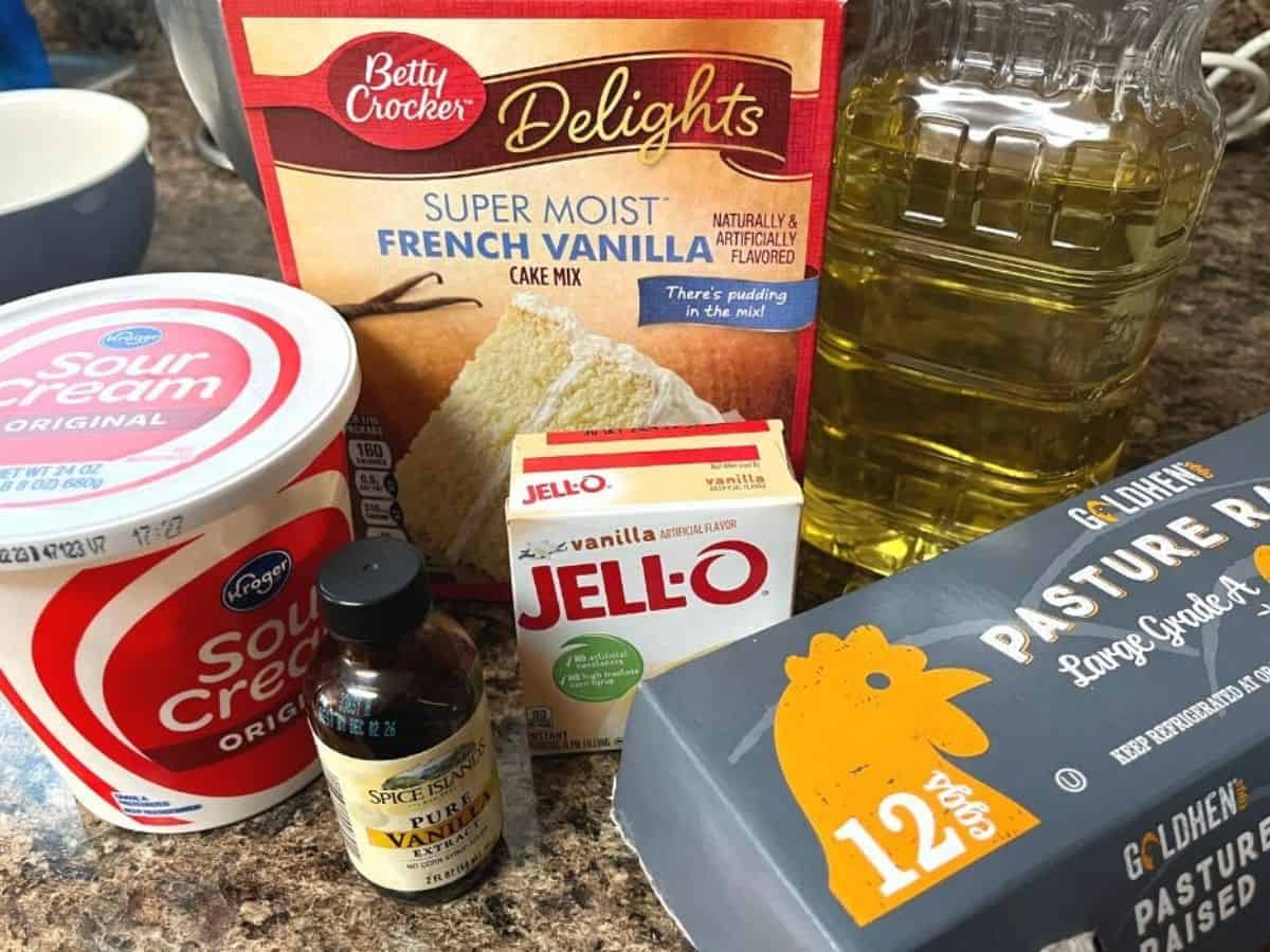 ingredients for making vanilla pudding cake, including french vanilla cake mix, instant vanilla pudding mix, sour cream, oil, eggs, and vanilla extract