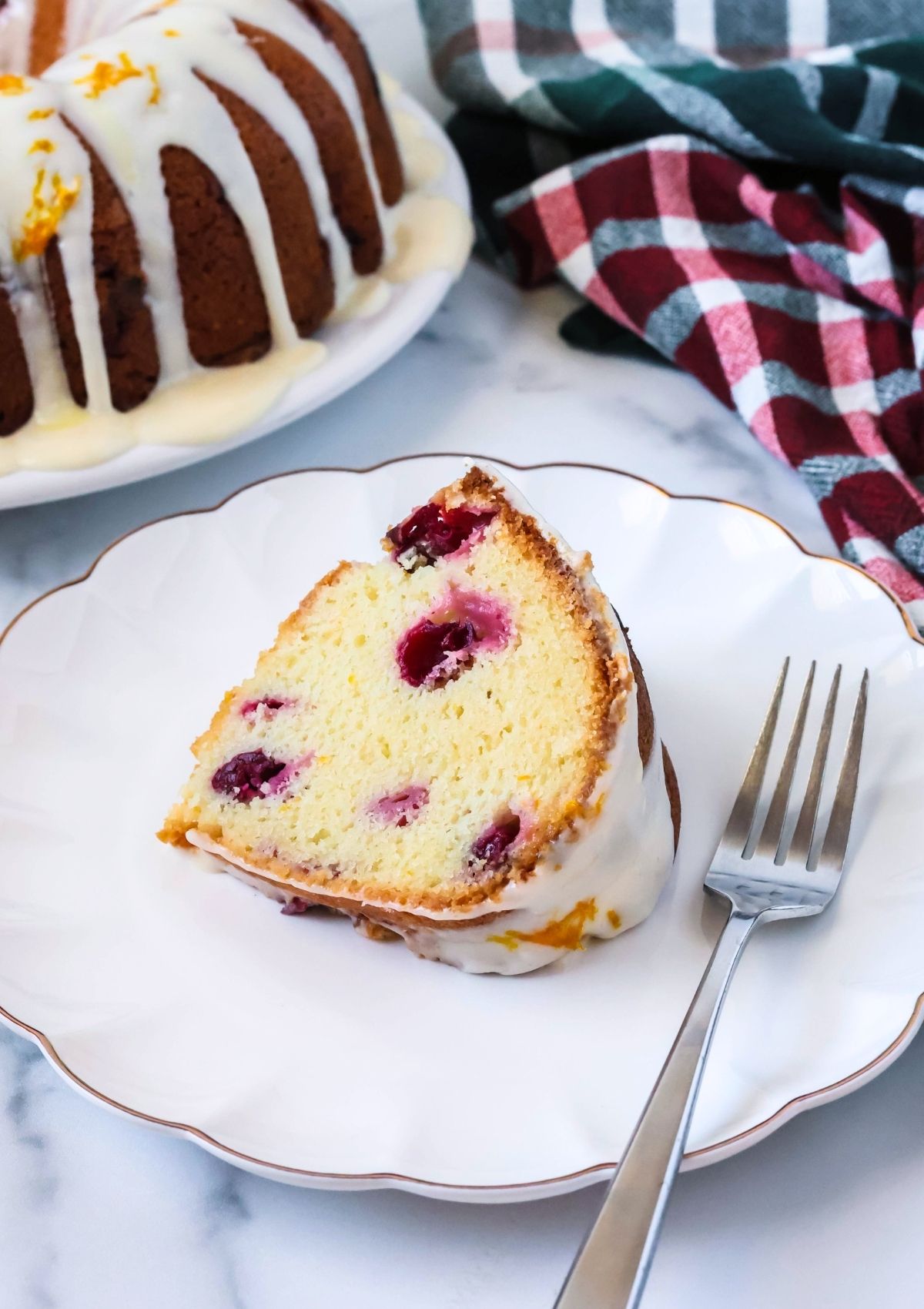 Close-up view of a slice of cake mix cranberry orange bundt cake served on a white plate with a fork.
