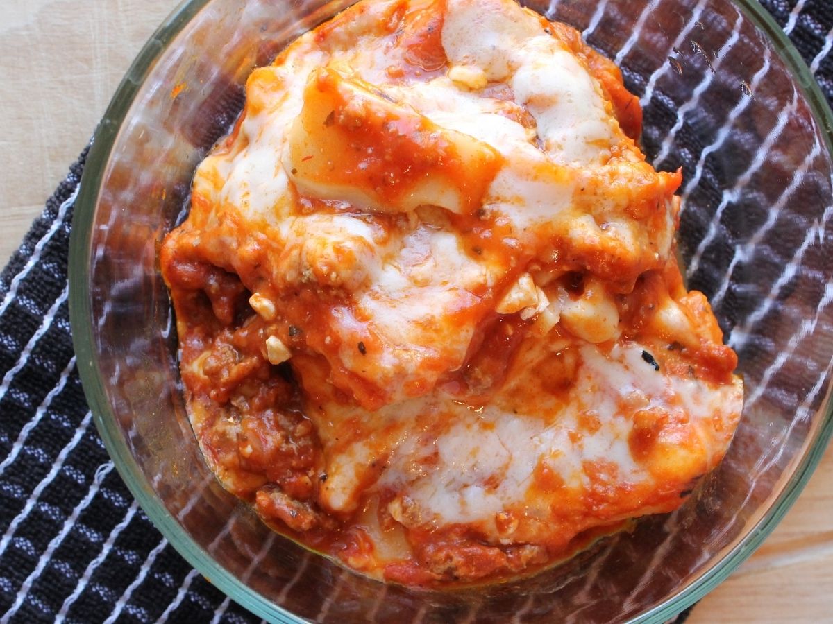 Glass dish of lasagna that was reheated in the Instant Pot, showing the melted cheese and tender noodles in sauce.