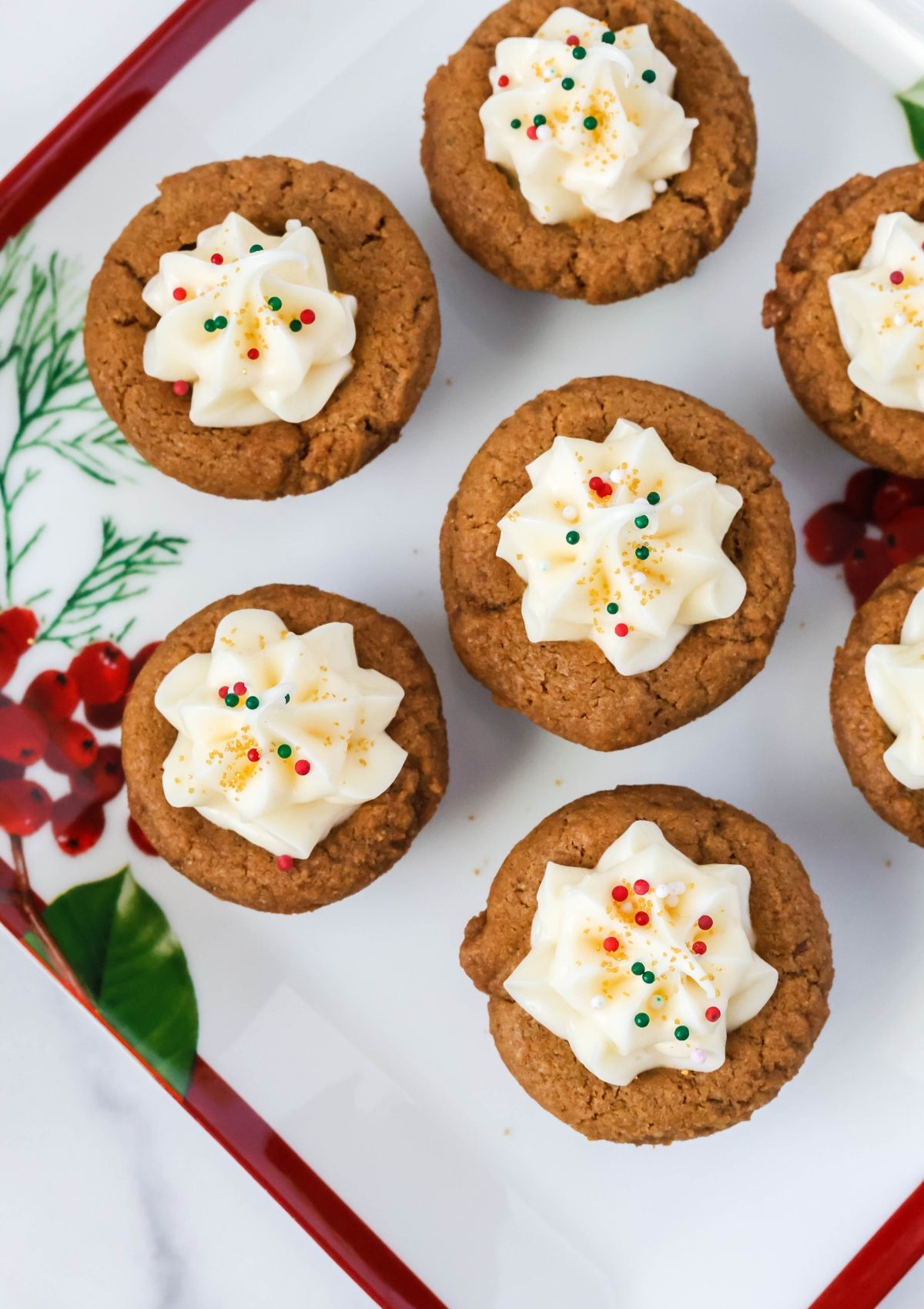 Overhead view of gingerbread Christmas cookie cups topped with frosting and holiday sprinkles.