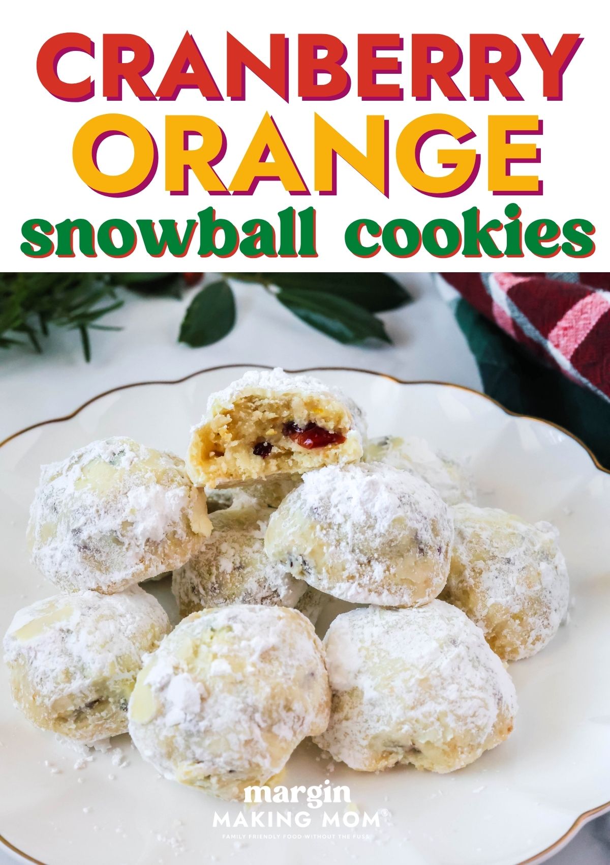Cranberry orange snowball cookies on a white plate; one cookie has a bite taken out of it to showcase dried cranberries inside the cookies.