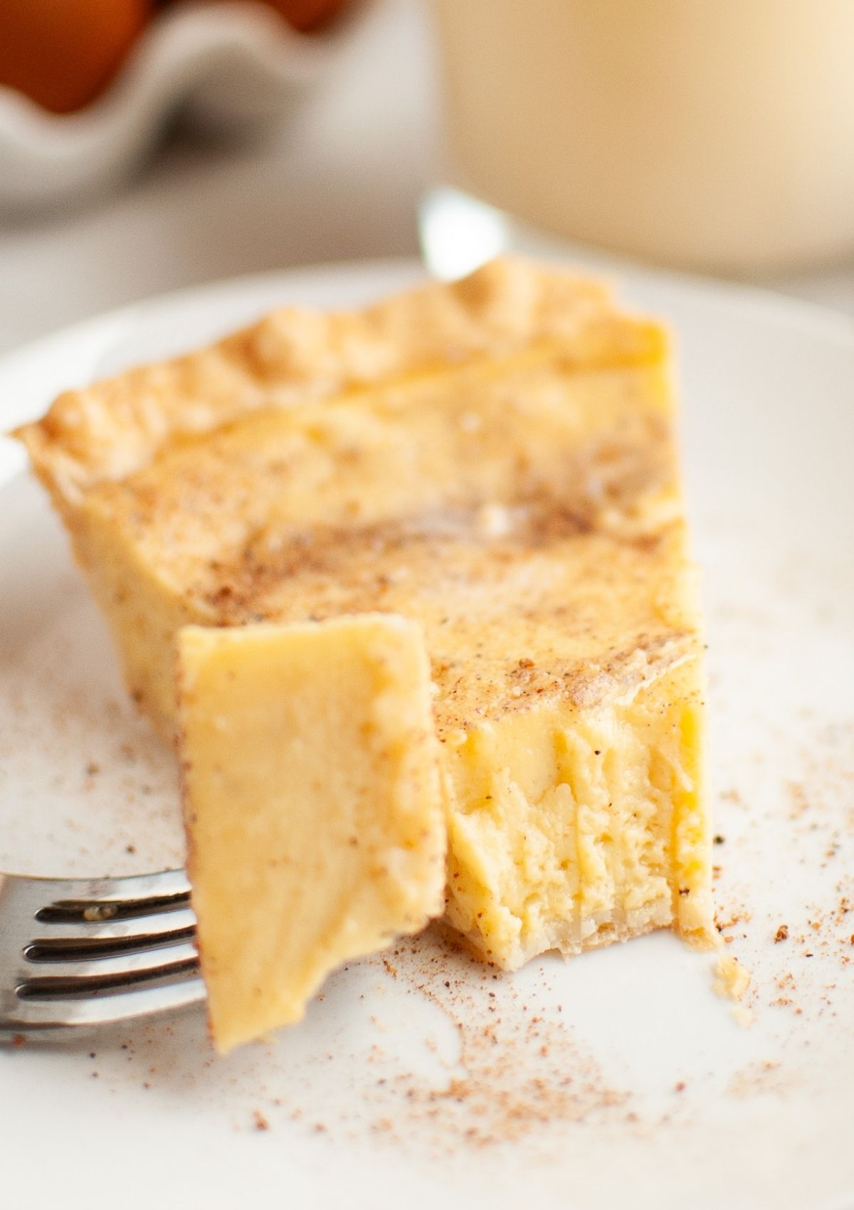 Slice of eggnog Christmas pie with a bite tkaen out of it by a fork.