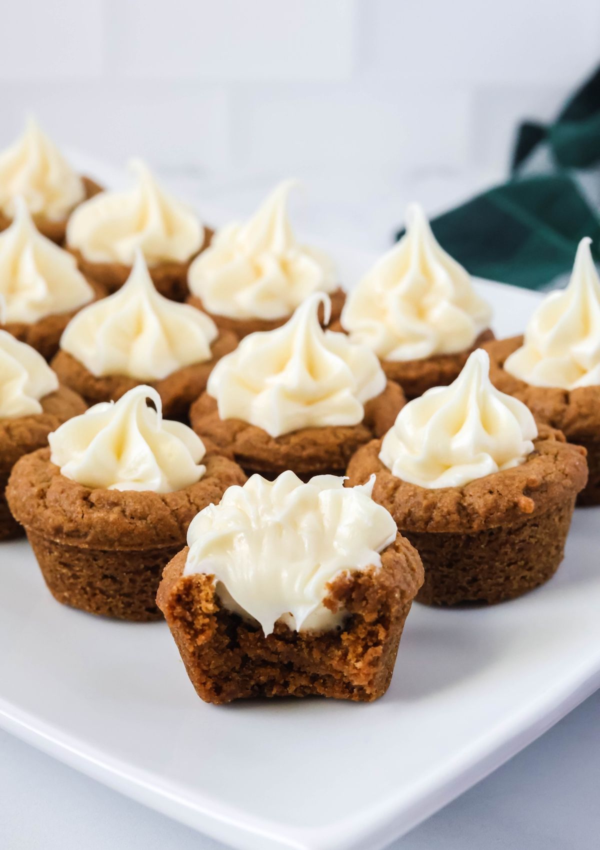 Gingerbread cookie cups on a white platter, one of which has a bite taken out of it.