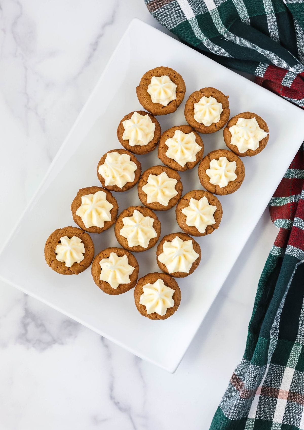 Overhead view of a white rectangular platter with several frosted gingerbread cookie cups displayed on it.