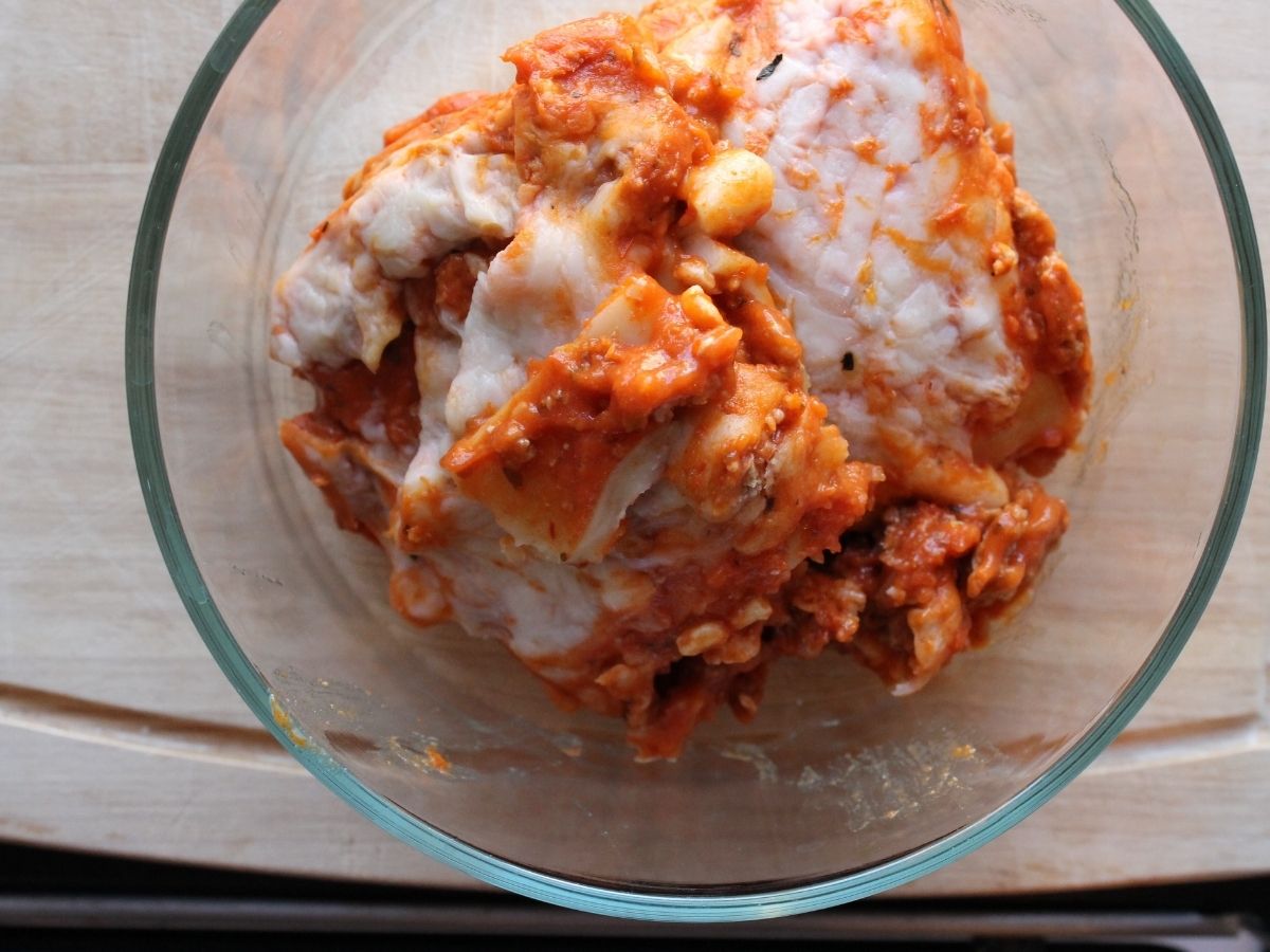 Overhead view of a glass bowl filled with leftover lasagna that will be reheated in the Instant Pot.