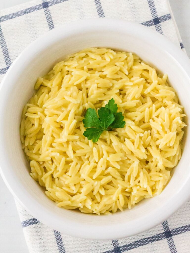 Instant Pot orzo pasta served in a white bowl, garnished with fresh parsley.